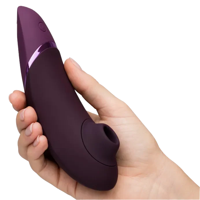 Hånd holder lilla Womanizer NEXT klitorisstimulator med sugåpning